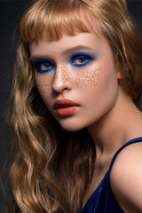 High fashion close-up portrait of a young beautiful model with trending makeup and hairstyle. Artificial freckles. Fashionable bobbed bangs. Perfectly healthy skin. Smoky eye makeup.