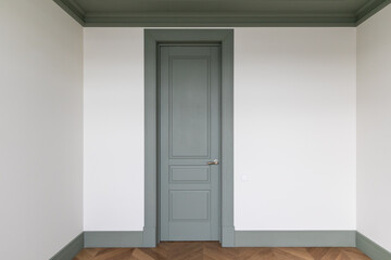 Classic interior small room with french herringbone parquet floor and green door and skirting boards. The final stage of finishing works in the apartment