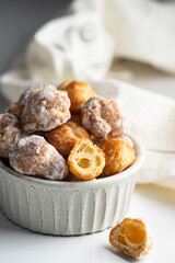 Bunuelos, Spanish small deep fried doughs in ceramic bowl on white background with napkin.