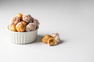 Bunuelos, Spanish small deep fried doughs in ceramic bowl on white background with napkin.