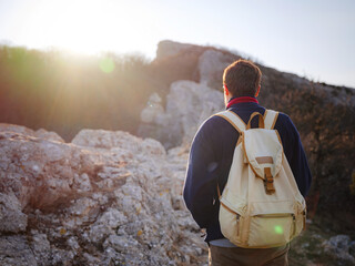 A man on top of a cliff in the spring mountains at sunset and enjoying the view of nature