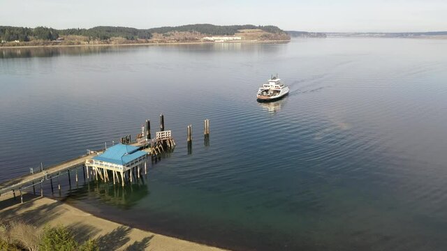 Cinematic drone aerial footage of the arriving ferry at the ferry terminal with cars on Anderson Island, Puget Sound near Mc Neil island, Steilacoom, Tacoma, Washington