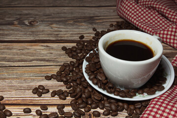 hot black Coffee cups and coffee beans and red plaid cloth on a wooden background, close up.