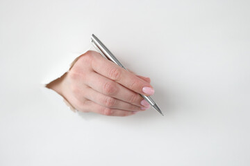 Female hand holds pen through hole in white paper