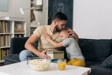 father and son sharing gifts at home