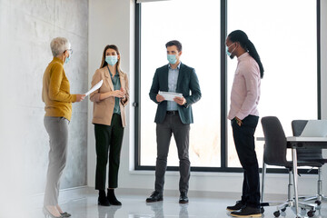 Happy business people wearing masks working in office