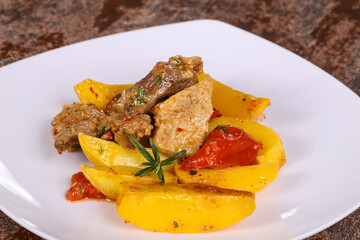 Baked pork meat with potao and tomato