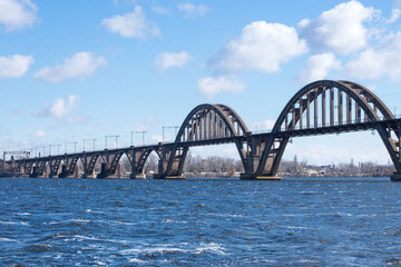 Metal bridge over the Dnieper river in the Ukrainian city of Dnieper (Dnepropetrovsk). Nice view of the river in early spring. Travel across Ukraine.