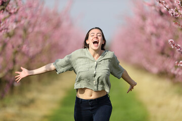 Happy woman running celebrating vacation in a field