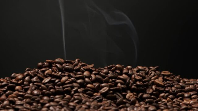 Close up macro coffee beans 4K. Roasting coffee seeds on black background slow motion