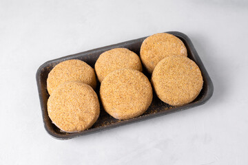 Semi-finished frozen fish cutlets in breading. Raw fish burgers, white background. Fast cheap food, saves time in the kitchen. Hand made, lean recipe idea