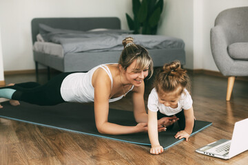 A young sports mom and a girl together do exercises at home. Healthy development of parents and...