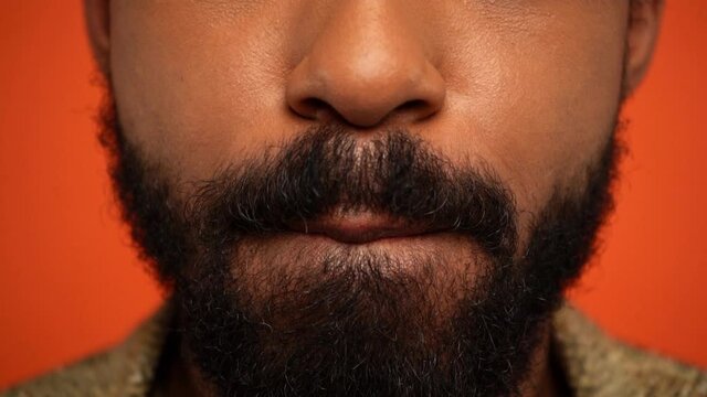 partial view of bearded of african american man licking lips isolated on orange