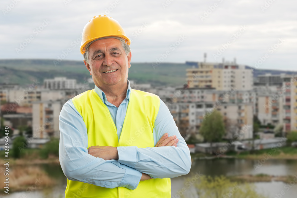 Wall mural friendly construction worker with crossed arms town background