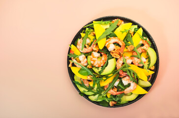Summer Salad with Mango, Shrimps and Avocado, Walnut, Spinach and Arugula. Healthy Eating food concept Top view, pink background