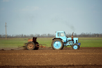 Blue tractor cultivating soil in spring,agriculture industry photo