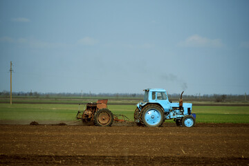 Blue tractor cultivating soil in spring,agriculture industry photo