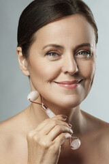 Beautiful middle aged woman using rose quartz derma roller
