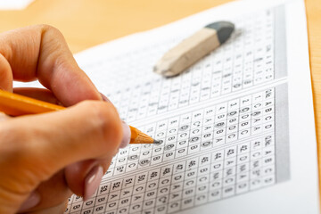 The student fills in the answers to the test in the exercise and examination paper with a pencil. education concept.