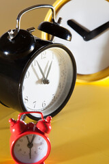 Three alarm clocks in different styles, sizes and colors. Yellow background