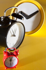 Three alarm clocks in different styles, sizes and colors. Yellow background