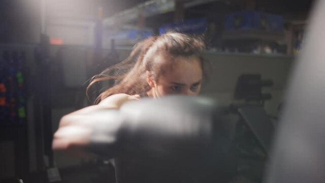 Female boxer punching boxing bag during training in gloves