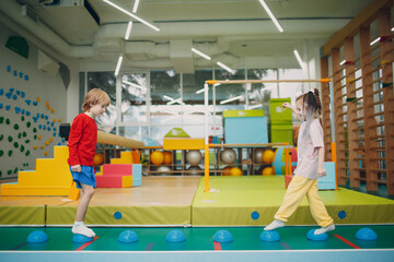 Kids doing massage hedgehog for foot legs exercises in gym at kindergarten or elementary school....