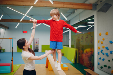 Kids doing balance beam gymnastics exercises in gym at kindergarten or elementary school. Children...