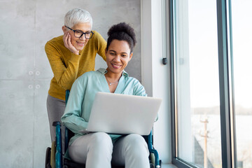 Happy business woman with disability in wheelchair working in corporate office