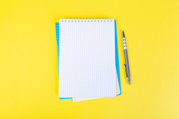 open notepad on yellow background with pencil on top, spiral notepad with blank sheet.