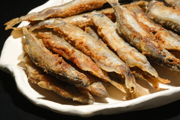 Pan fried fish on a plate. Small crispy fish. Capelin fried in oil with crispy breading. Selective focus