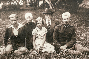 Latvia - CIRCA 1930s: People sitting on ground. Group photo in forest. Vintage archive Art deco era photo
