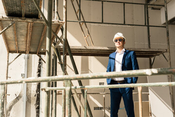 Architect or businessman wearing formal suit and hard hat on a construction site