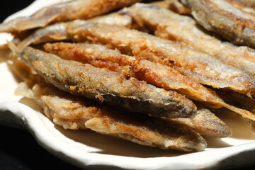 Pan fried fish on a plate. Small crispy fish. Selective focus