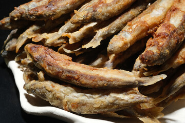 Pan fried fish on a plate. Small crispy fish. Capelin fried in oil with crispy breading. Selective focus