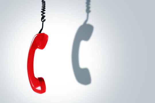 Red telephone handset with a dark shadow. Concepts of hotline, support or phone scams.