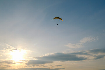 Paraglider flying into the sunset. Sky and sun landscape.