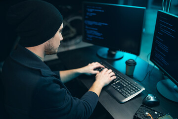 Hacker wearing a sweatshirt and cap tries to hack a security system to steal or destroy critical...