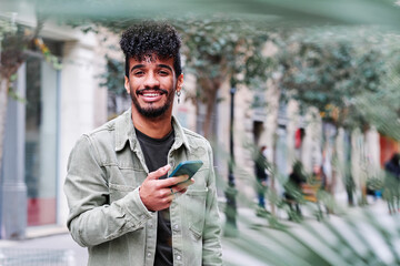 a young hipsanic man using his mobile phone outdoors in a cloudy day