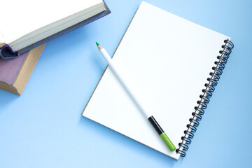 Stack of colorful old hardback books with open notebook and pencil. Online education. Top view