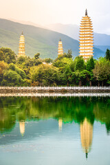 Beautiful scenic vertical view of Dali Three Pagodas of Chongsheng Temple with water reflection and dramatic light Dali Yunnan China