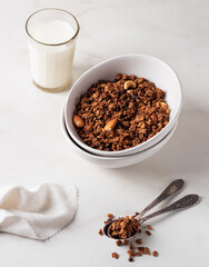 Homemade chocolate granola in a white plate with milk on a light background. Healthy breakfast