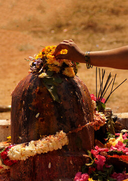 view of Indian Hindu woman offer prayers to stone carved god Shiva in shape of Lingam on maha shivaratri