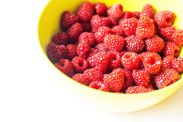 Close-up of ripe raspberry fruits on a bamboo plate on the table.