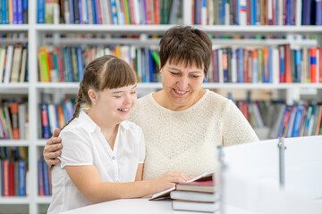 Fototapeta na wymiar Teacher and girl with syndrome down read a book at library. Education for disabled children concept