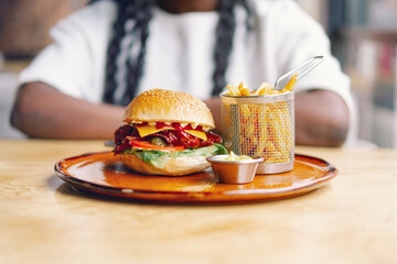 African woman with afro hair eating a tasty classic burger with fries.