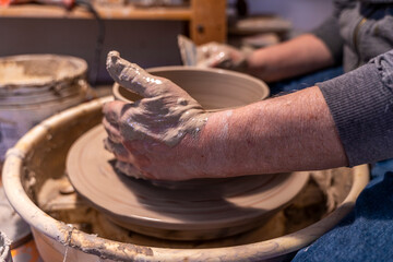 close-up on male hands working on a potters wheel to make a bowl