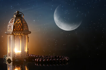 Muslim lamp and tasbih on table against night sky © Pixel-Shot