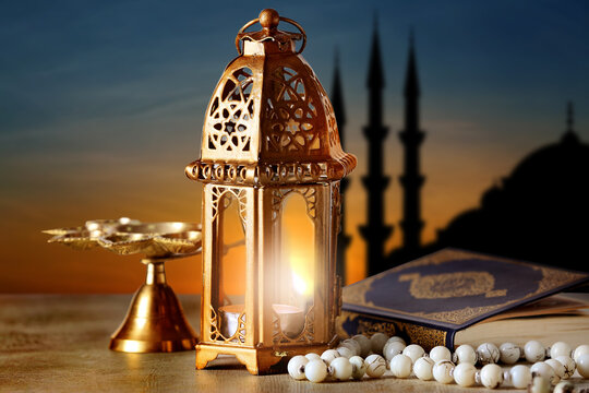 Muslim lamp, tasbih and Koran on table at sunset
