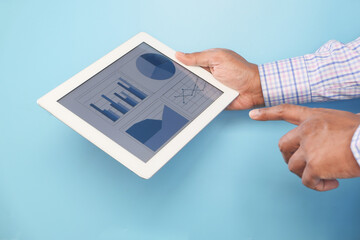 man's hand working on digital tablet against blue background 